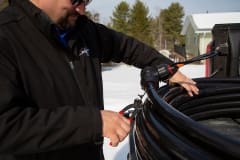 Contractor cutting zip ties to uncoil Heat-Line Freeze Protected Pipe System on Tailgate
